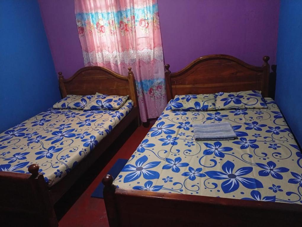 - une chambre avec 2 lits avec des fleurs bleues et blanches dans l'établissement River side resort, à Balangoda