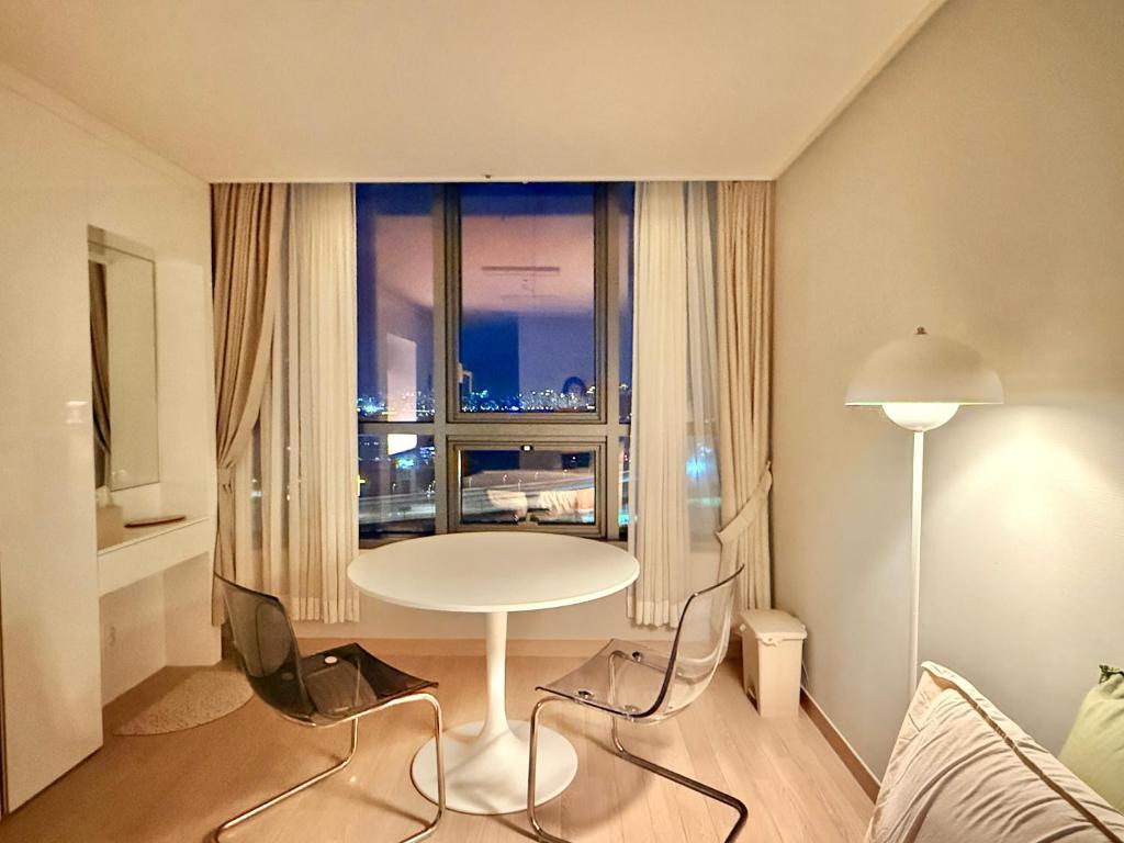 ein Wohnzimmer mit Tisch und großem Fenster in der Unterkunft Shine Stay 5 Min from Songdo Moonlit Festiv Park Station in Taeam