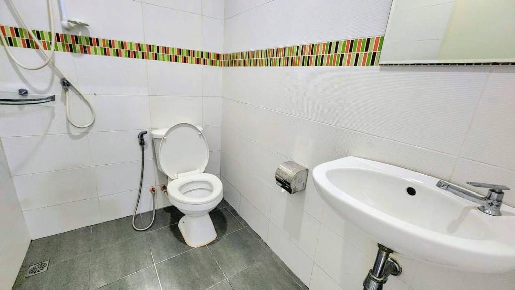 A compact tiled bathroom with a toilet, wall shower, handheld bidet, and basin.
