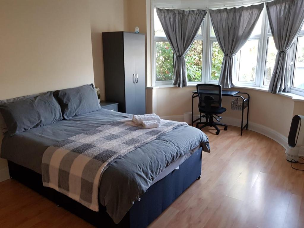 Un dormitorio con una cama y una silla y ventanas. en Hendon Home, en Hendon