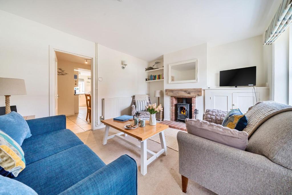 a living room with two blue couches and a table at Avocet Cottage in Brancaster