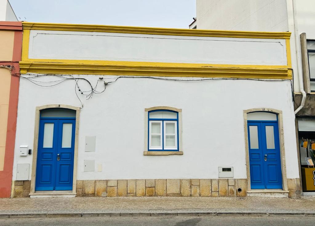 two blue doors on a white building at Casa Eliz Modern Comfort in the center of Faro in Faro