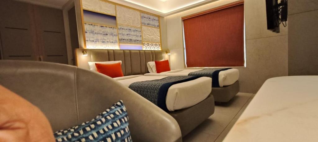 a hotel room with two beds and a chair at SILVER INN, Andheri in Mumbai