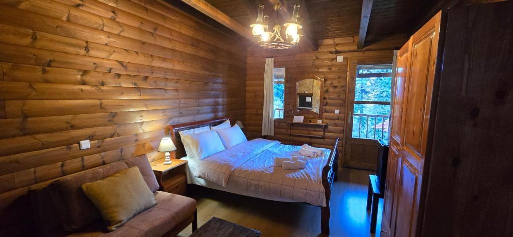 a bedroom with a bed and a couch in a log cabin at Panorama Elati in Elati Trikalon