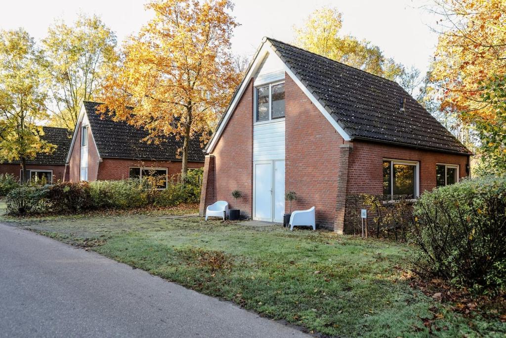 une maison en briques avec deux bancs blancs devant dans l'établissement Holiday home with sauna on Panjevaart - VP100, à Hoeven