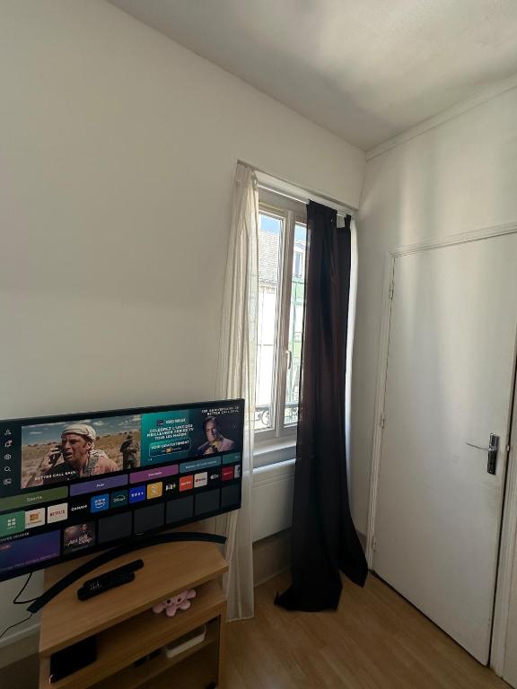 a living room with a television and a window at Bright apartment, 5 minutes from Paris in Asnières-sur-Seine
