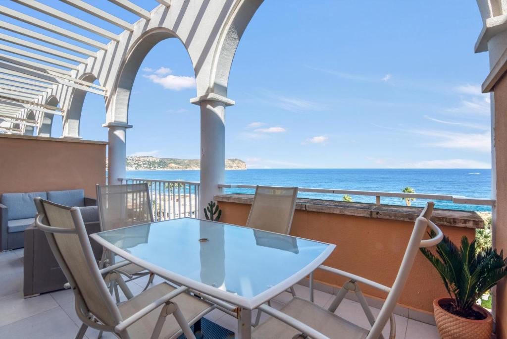 a table and chairs on a balcony with a view of the ocean at Jávea Beachfront Penthouse in Platja de l'Arenal