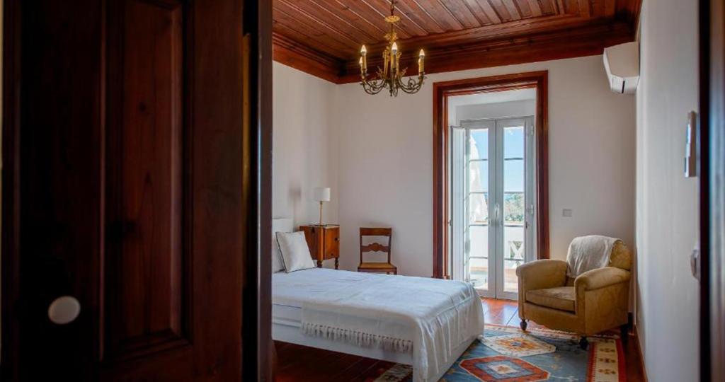 een slaapkamer met een bed, een stoel en een raam bij Ria Endless South - Barroca Village - Sítio da Fortaleza in Tavira