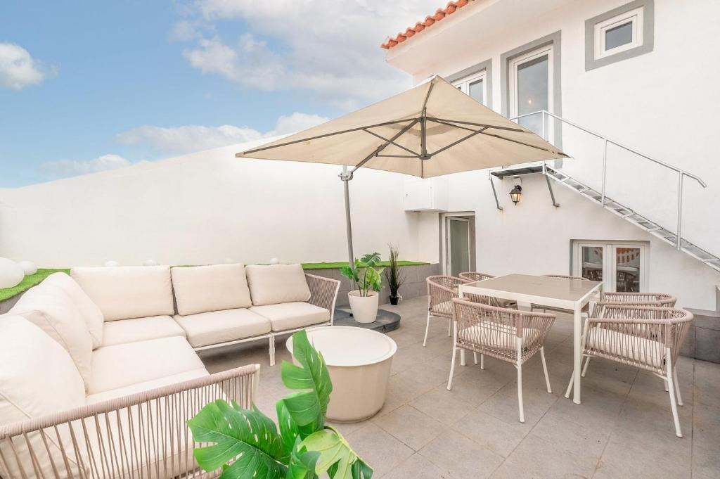 a patio with a couch and an umbrella at Guest Ready - Charming Retreat in Palmela in Palmela