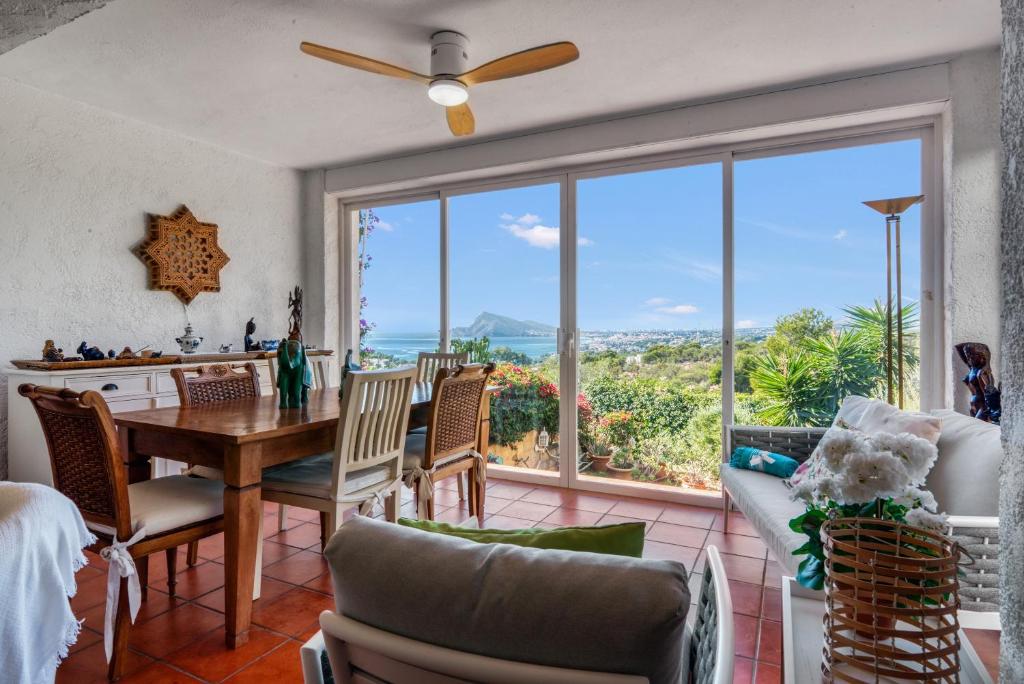 Un comedor con mesa y sillas y una gran ventana. en Oceanview House Altea Hills, en Altea la Vieja