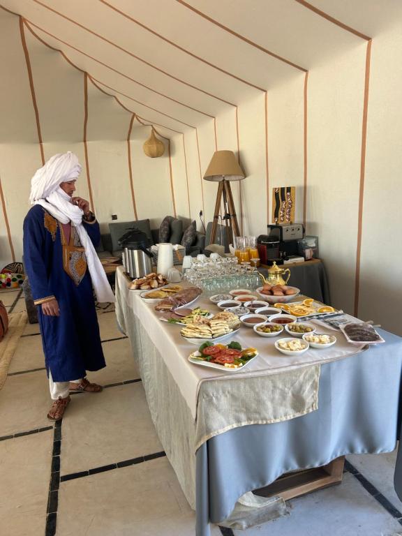a woman standing in front of a table of food at Dream Luxury Majestic Camp in Merzouga