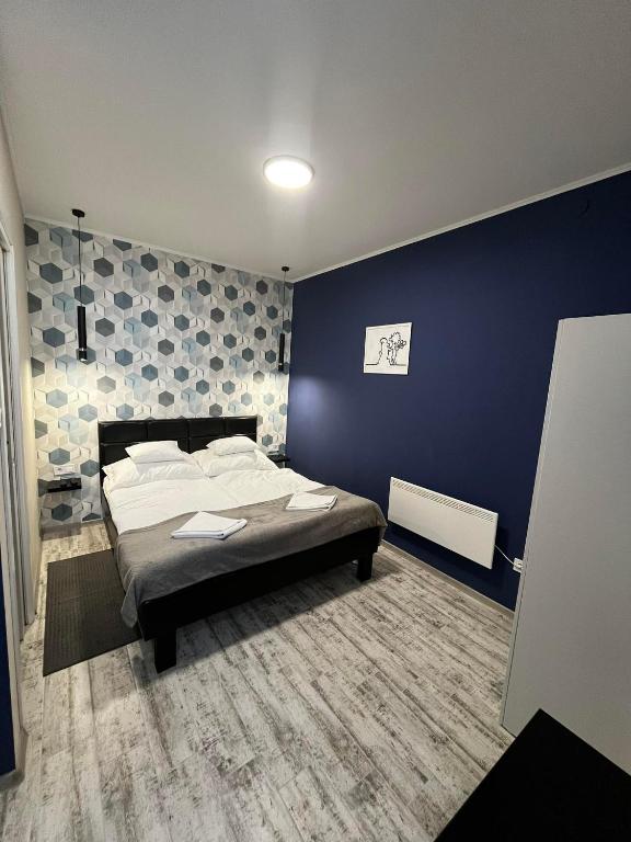 a bedroom with a bed and a blue wall at Margaréta Studió Apartman in Hódmezővásárhely