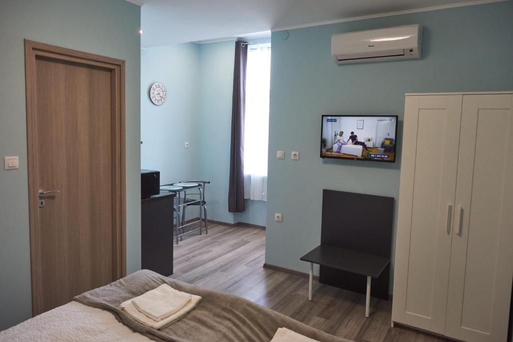 a bedroom with a bed and a tv on the wall at Margaréta Studió Apartman in Pusztavacs