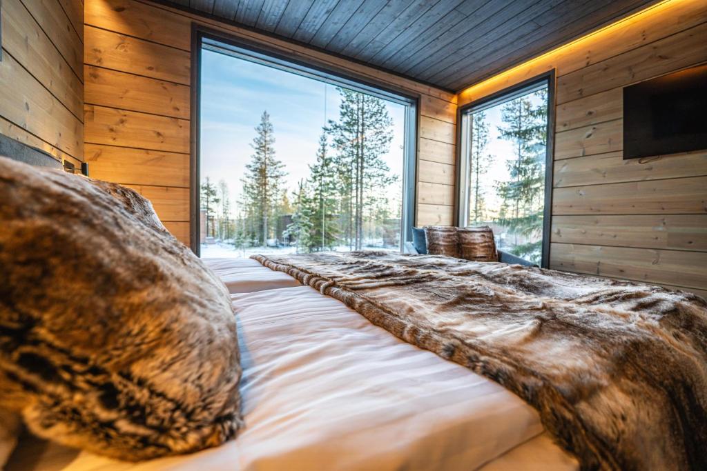a large bed in a room with a large window at Aurora Hill Resort, Rovaniemi in Rovaniemi