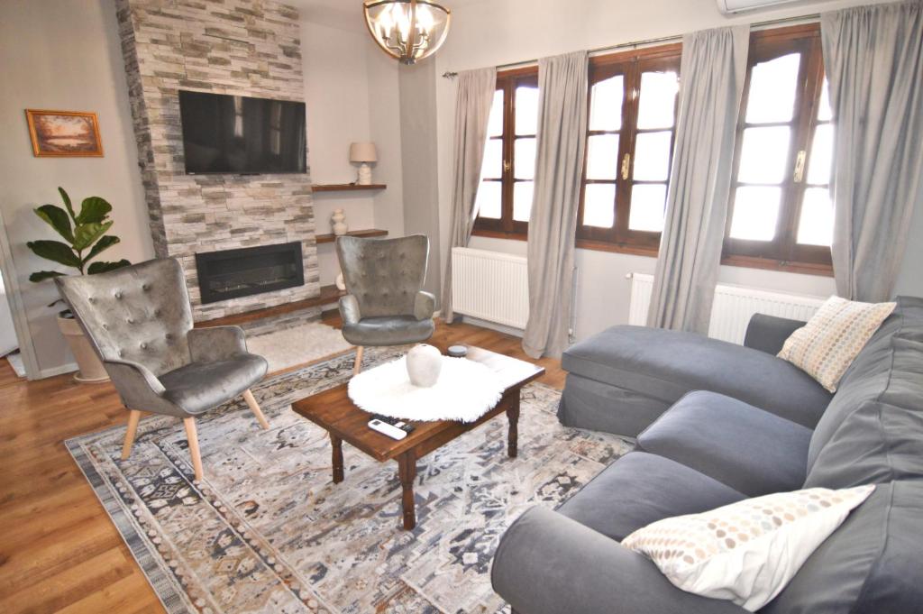 a living room with a couch and chairs and a fireplace at Apozari Xenias Apt in Kastoria