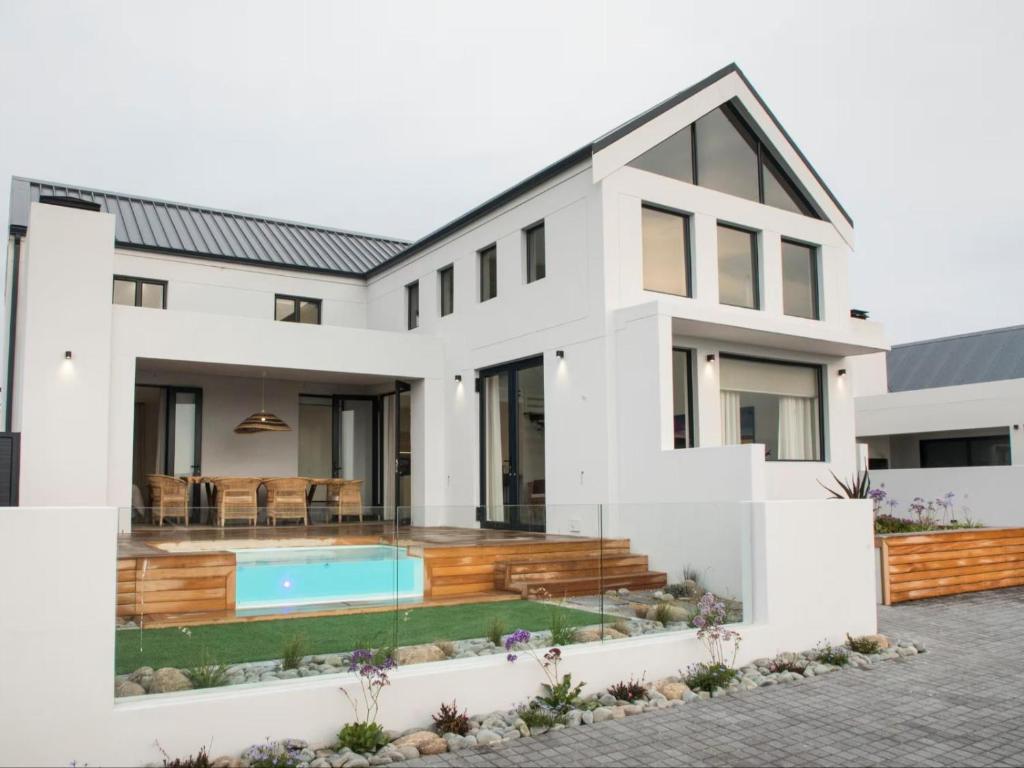 a white house with a swimming pool and a patio at Yzer Heights Relaxed Luxury Stay in Yzerfontein