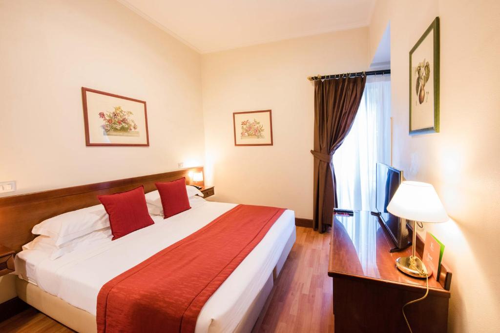 ein Hotelzimmer mit einem großen Bett mit roten Kissen in der Unterkunft Hotiday Roma Borghese in Rom