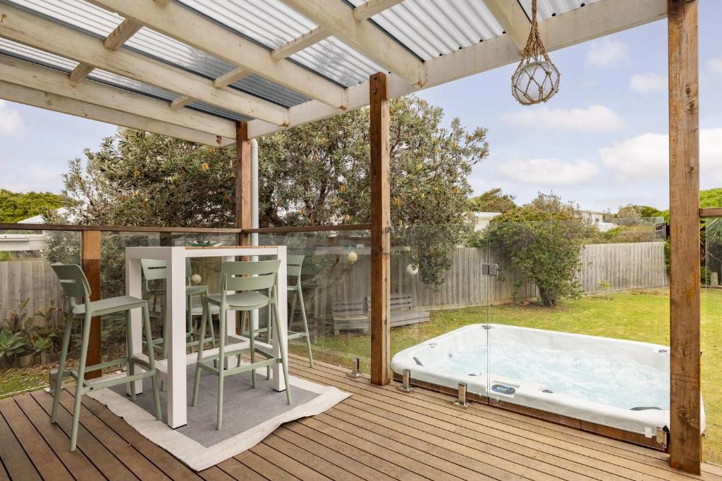 una terraza con bañera de hidromasaje, mesa y sillas en Good Vibes at Surf Beach with Spa, en Surf Beach