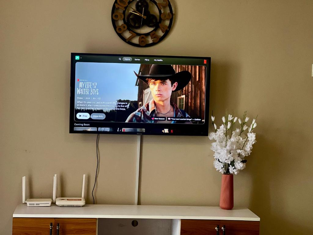 Un televisor de pantalla plana en una pared con un reloj. en Zuri home 2, en Kampala