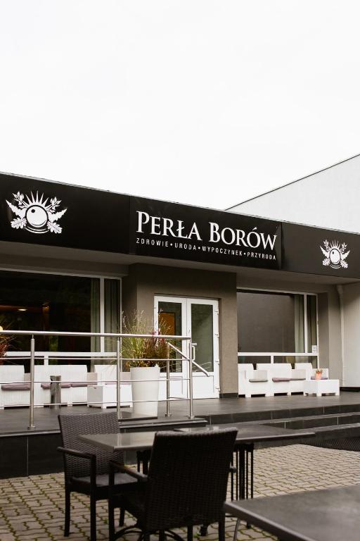 a restaurant with a table and chairs in front of a building at Ośrodek Wypoczynkowo-Rehabilitacyjny Perła Borów in Tleń