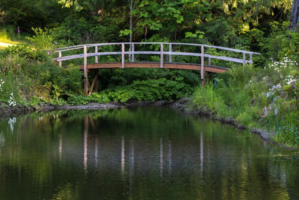 a wooden bridge over a pond in a garden at A Hidden Haven Cottages in Port Angeles