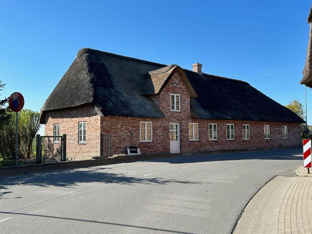 un grande edificio in mattoni rossi con tetto di paglia di Hyggehouse-Unser-Ferienhaus-an-der-deutsch-daenischen-Grenze a Rudbøl