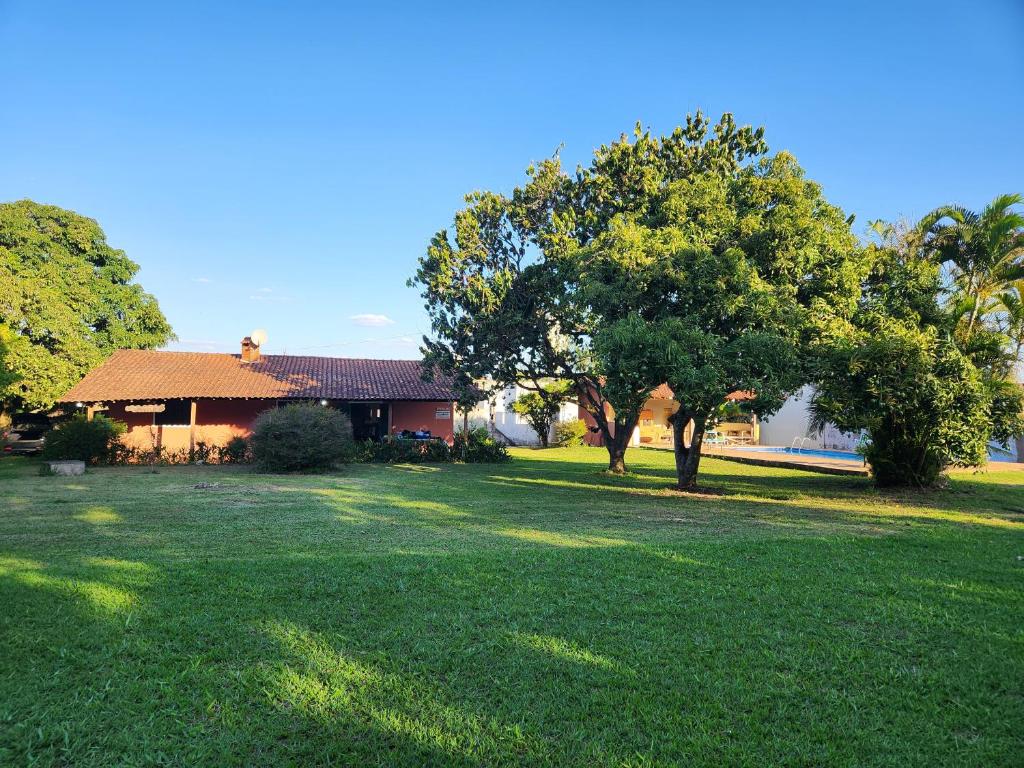 a house with a green yard with a tree at Refúgio com Piscina, Churrasco e Lazer no Campo in Sumaré