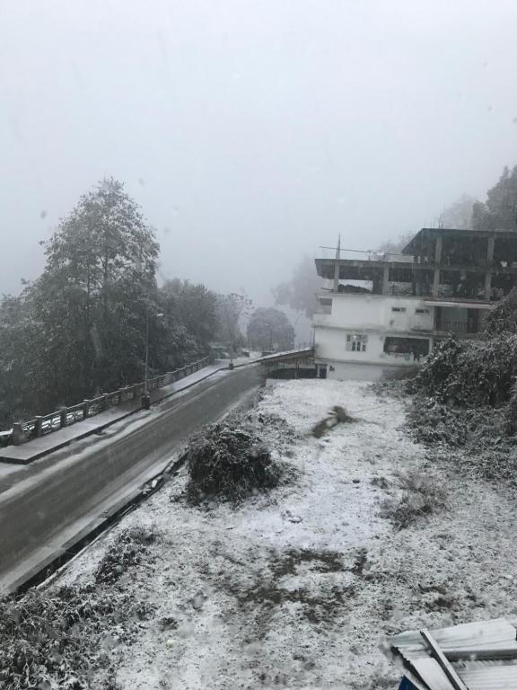a road with snow on the ground next to a building at Shenga Homestay in Ravangla
