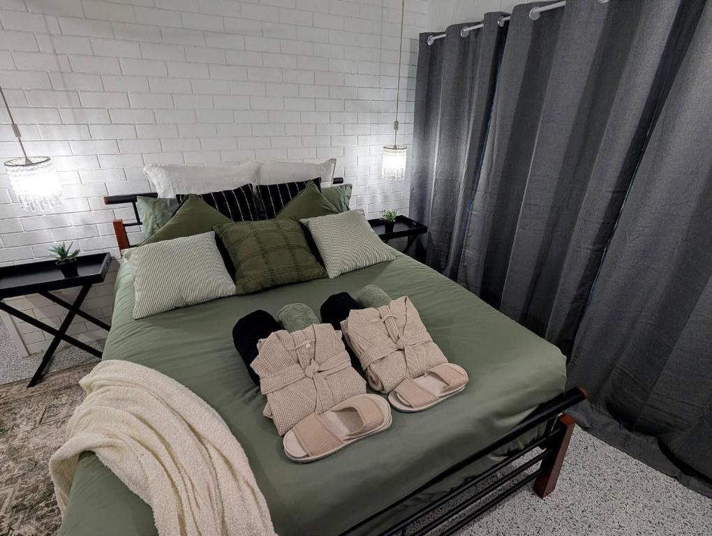ein Bett mit zwei Paar Hausschuhen drauf in der Unterkunft Peaceful, Modern, LowToxic, Bfast included in Brisbane