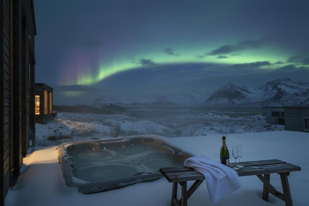 a hot tub in the snow with a rainbow in the sky at Serene cabin in Lofoten with sauna in Storøya