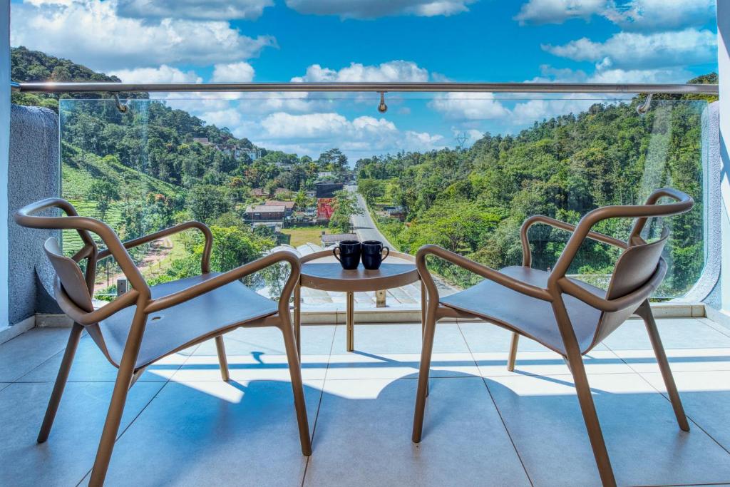 a balcony with two chairs and a table with a view at MYSA Sky Suites, Lakkidi in Vythiri