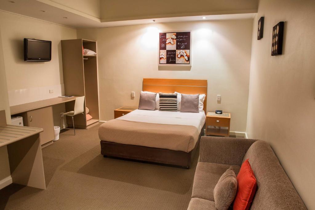 Habitación de hotel con cama y sofá en Burkes Hotel Motel, en Yarrawonga