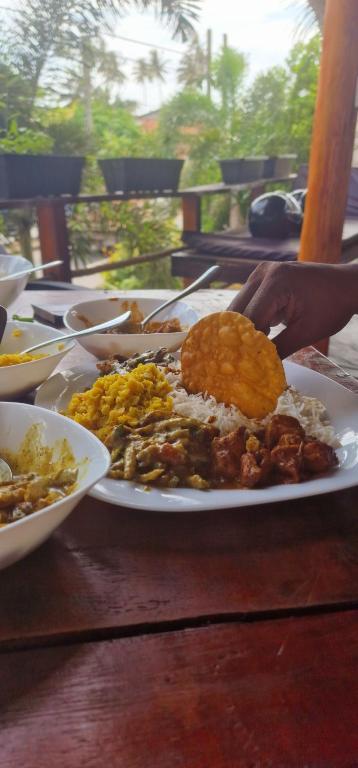 a plate of food on a wooden table at Lahima Cabanas in Dickwella