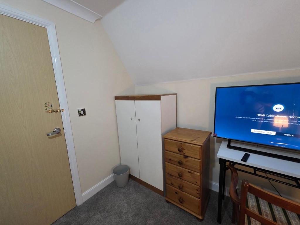 a room with a tv and a desk with a dresser at Guest Room in Colchester Hythe in Hythe