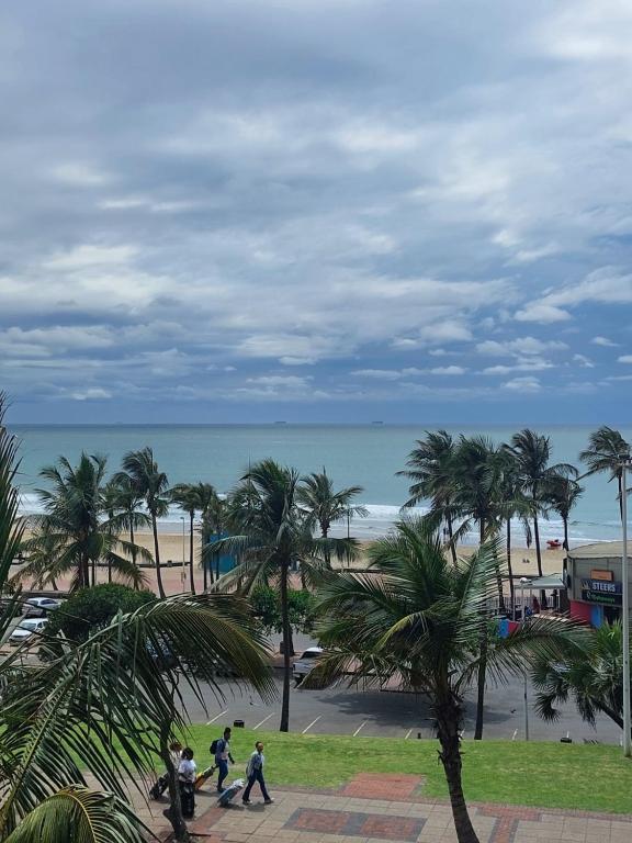 a group of people walking along a beach with palm trees at 27 on North Beach in Durban