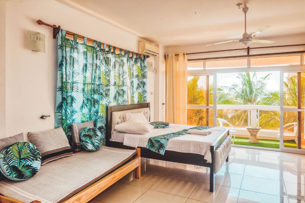 een slaapkamer met een bed, een bank en een raam bij Ocean Breeze Holiday Home Palace - 1st Avenue in Mombasa