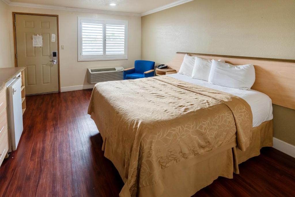una camera d'albergo con un grande letto e una sedia blu di Budget Inn Corcoran Near Tulare CA 43 a Corcoran