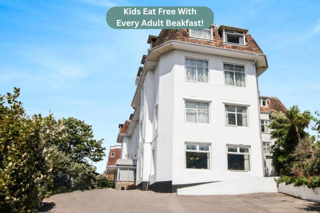 een wit gebouw met een bord waarop staat dat kinderen gratis eten bij elk ontbijt voor volwassenen bij Belvilla Russel Court Hotel Bournemouth Central in Bournemouth