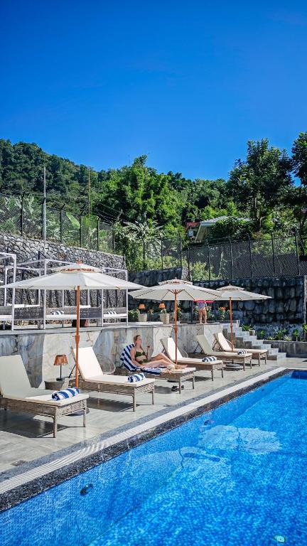 a group of lounge chairs and umbrellas next to a swimming pool at Hotel Mystic Mountain, Pokhara in Pokhara