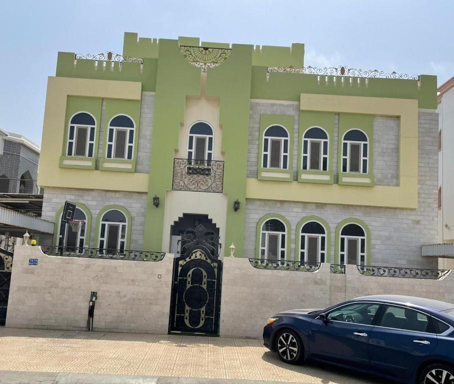 a blue car parked in front of a building at Kourosh in Muscat