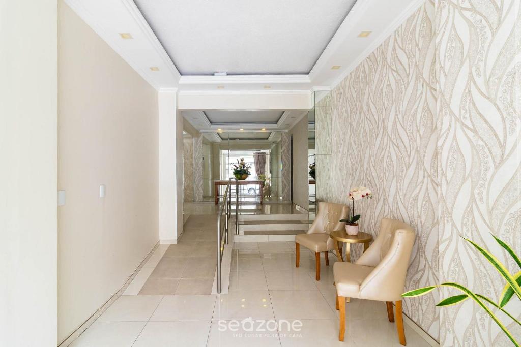 a hallway with white walls and chairs and a table at Aptos completos em Meia Praia a 150m do Mar - EOOs in Meia Praia