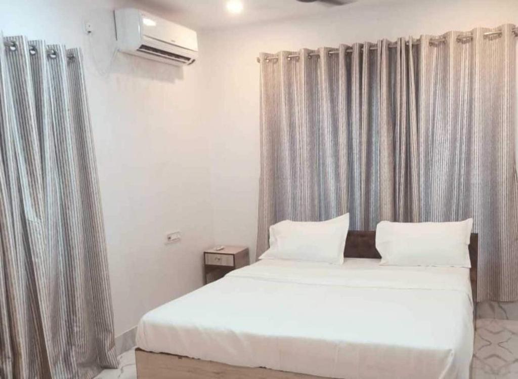 um quarto com uma grande cama branca com cortinas em Hotel O Shakuntala Park Bus Terminus Behala em Behāla