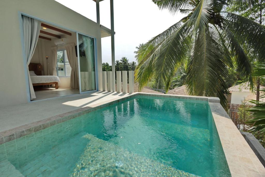 a swimming pool in front of a house at Peaceful Villa with Private Pool Garden Views by Sea N' Rent in Haad Chao Phao