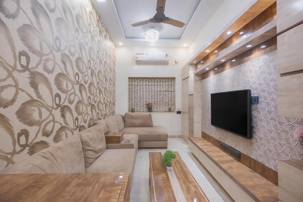 a living room with a couch and a tv on a wall at Royale Enclave by JadeCapsNr.Manipal Hosp. in Ballygunge