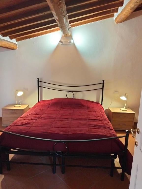 a bedroom with a red bed with two night stands at Zinfarosa Color Home in Foiano della Chiana