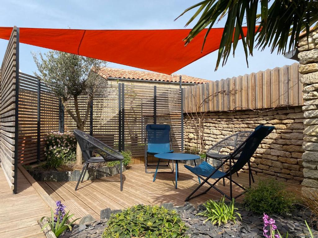 een terras met stoelen, een tafel en een parasol bij Charming house - Grand Village Plage in Grand-Village-Plage