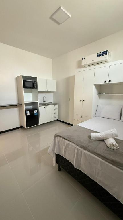 a white bedroom with a bed and a kitchen at Cabanos Prime Hotel e Residencial in Barcarena