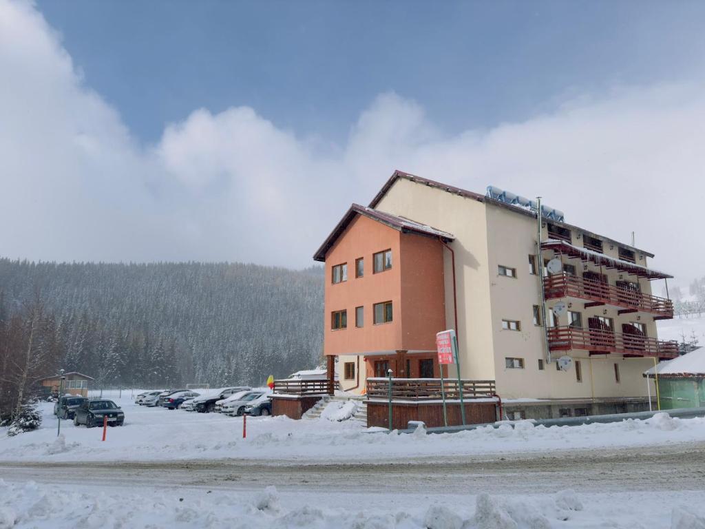 ein Gebäude auf einem Parkplatz im Schnee in der Unterkunft Pensiunea Turistică Octavian in Moroeni