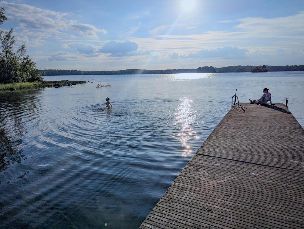 dos personas sentadas en un muelle en el agua en Boats stay play lake cabin, en Broby