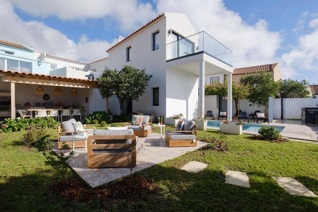 a large white house with chairs and a yard at Solar do Sabão - Your Gathering Place in Relva